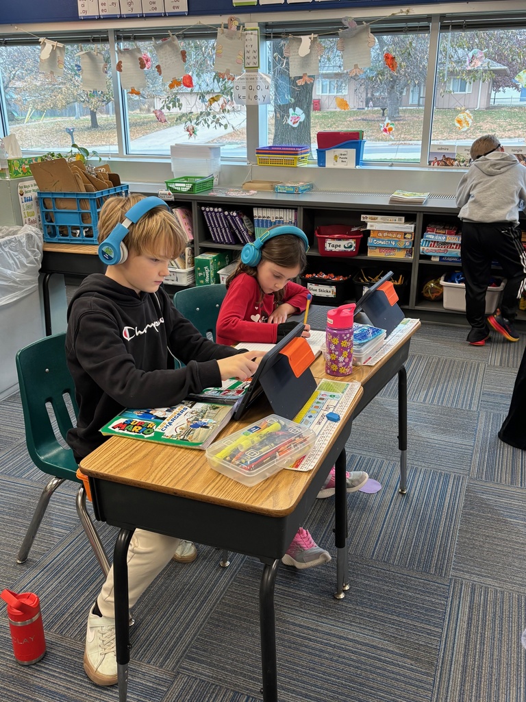 Group of 2nd graders sitting at their desks working with their headphones on and working on their iPads.