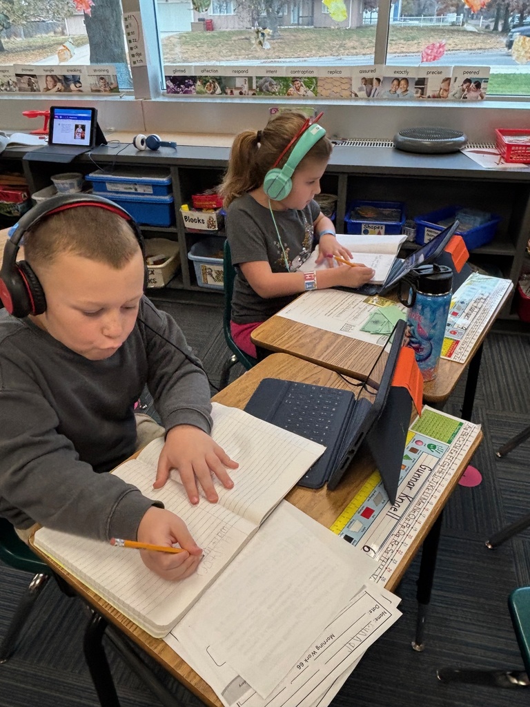 Group of 2nd graders sitting at their desks working with their headphones on and working on their iPads.