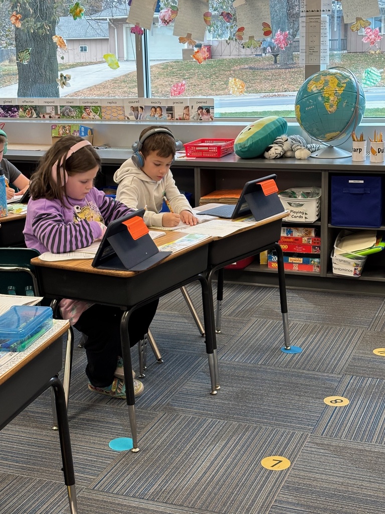 Group of 2nd graders sitting at their desks working with their headphones on and working on their iPads.