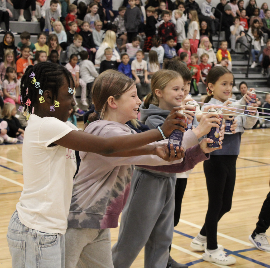 4th grade students grin as they spray the silly string on their teacher!
