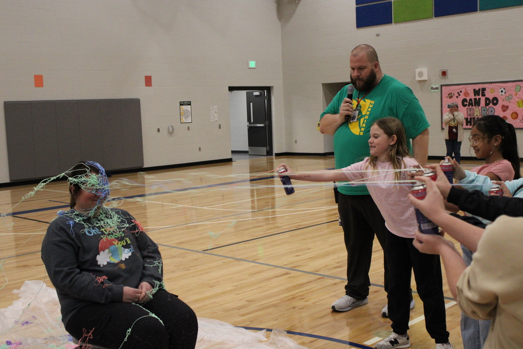 Mrs. Tipton sits as her students spray her with silly string. 