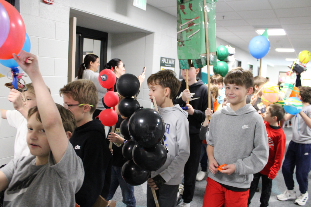 Students carry balloons as they walk in the parade together. 