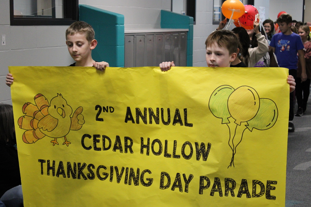 Two 5th grade students lead the parade with their Thanksgiving Day Parade sign. 