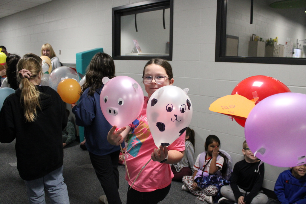 A 3rd grader shows off her cow and pig balloons in the parade. 