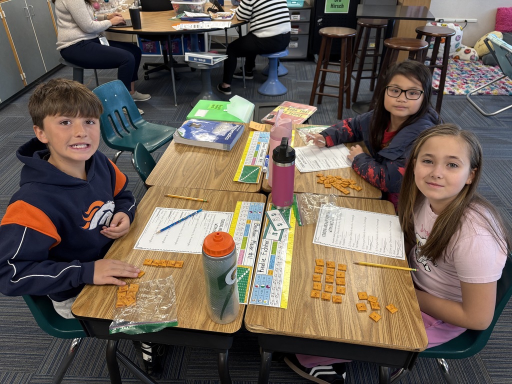 Group of kids sitting at desks with a paper in front of them and cheese its as well doing a math activity.