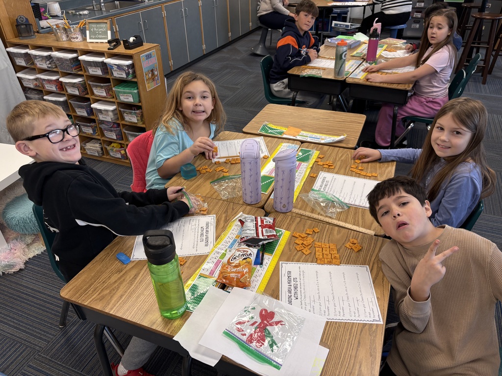 Group of kids sitting at desks with a paper in front of them and cheese its as well doing a math activity.