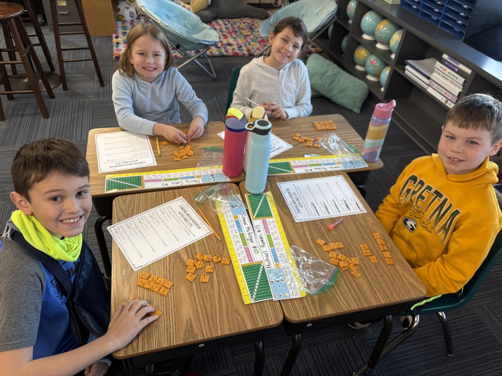 Group of kids sitting at desks with a paper in front of them and cheese its as well doing a math activity.