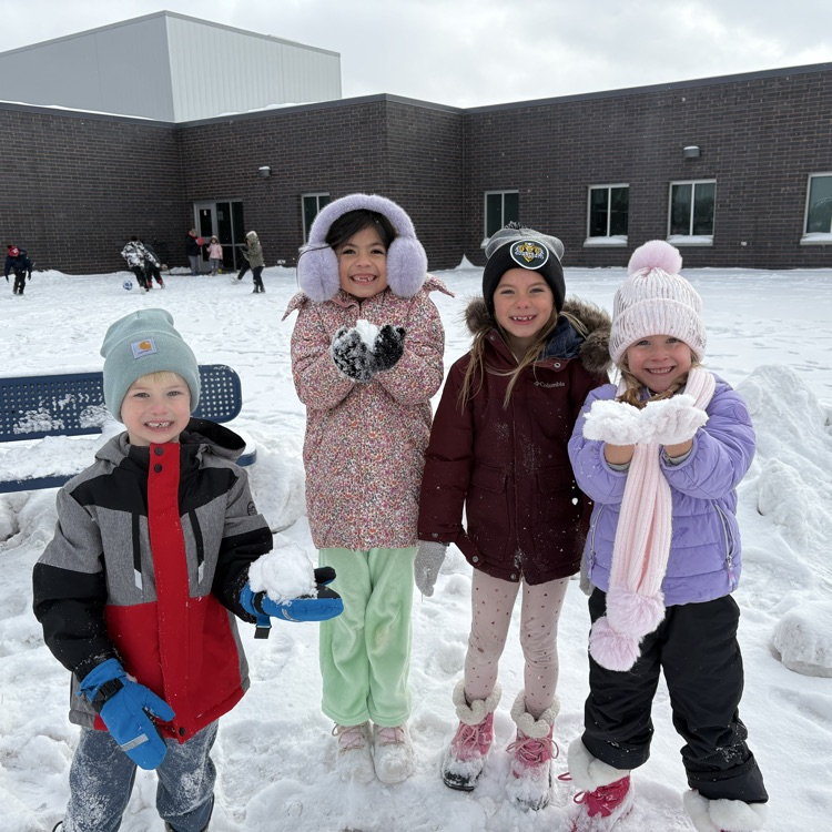 4 first graders are holding snow balls smiling  