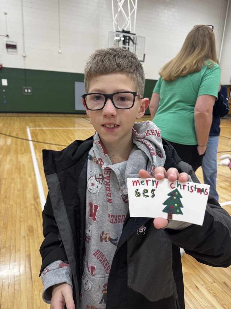 Boy holding a coffee sleeve that says Merry Christmas.