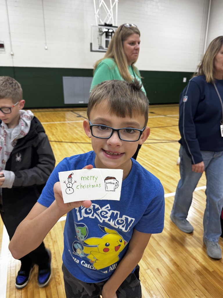 Boy holding a coffee sleeve that says Merry Christmas.