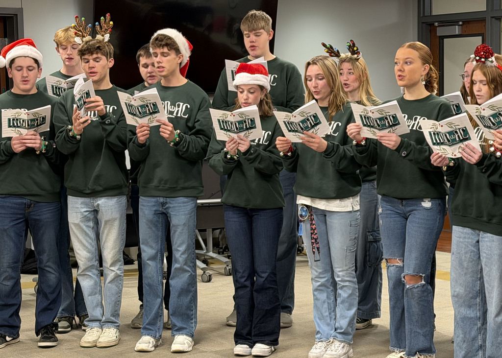 Group of singers in board room singing with sheet music
