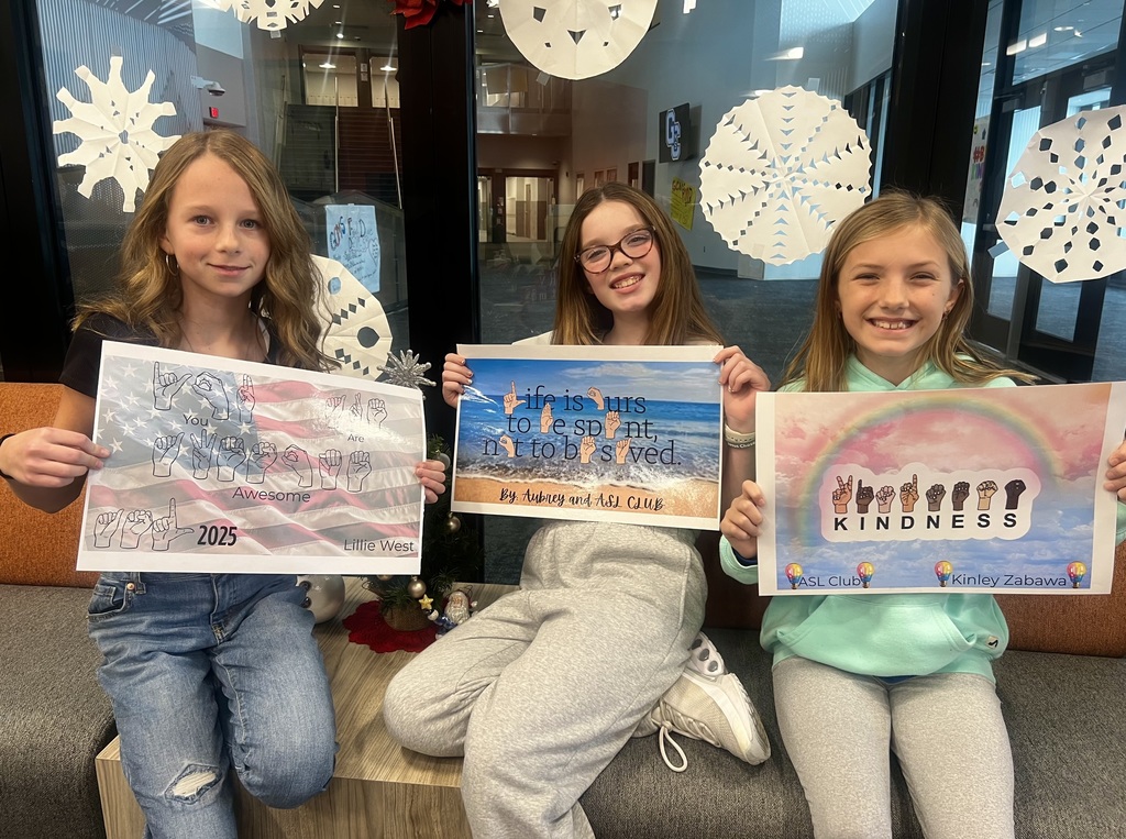 Three female students hold up posters for sign language club.