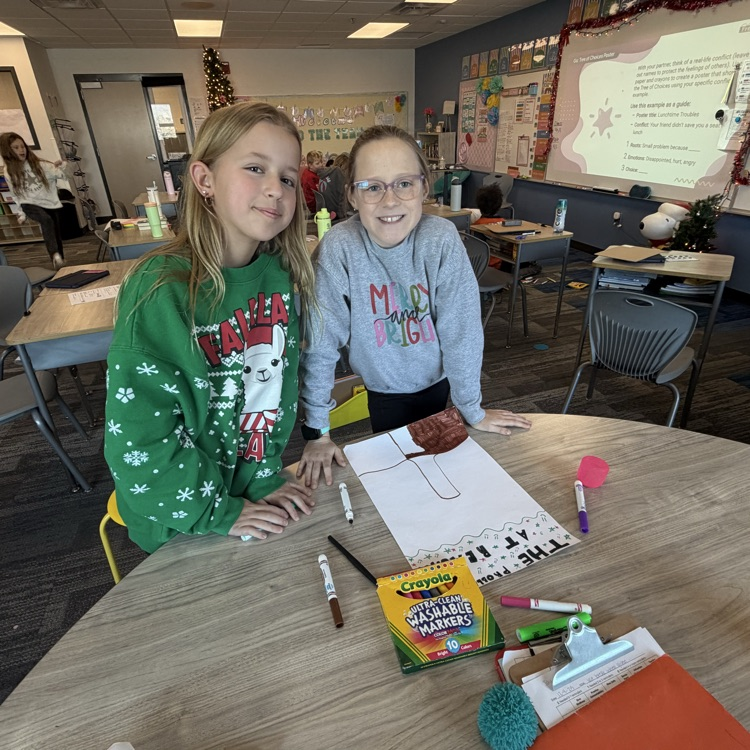 2 girls at a table making a poster