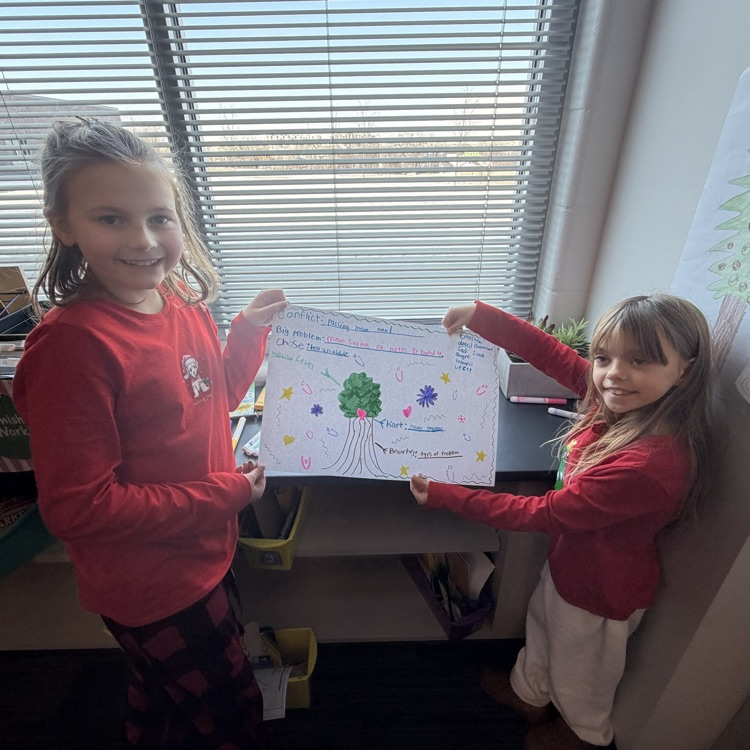 2 girls in red shirts hold up a poster