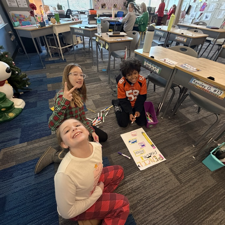 a group of three kids working on a poster on the floor