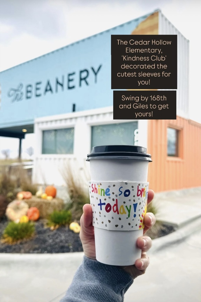 a coffee sleeve that says "Shine So Bright Today" on a cup with The Beanery in the background