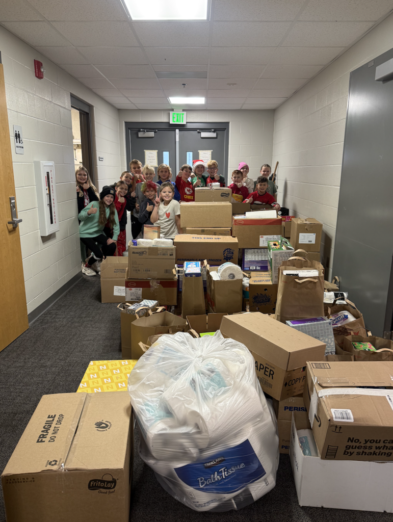 Picture showing students in our kindness club around all the boxes of items donated for Gretna Neighbors.