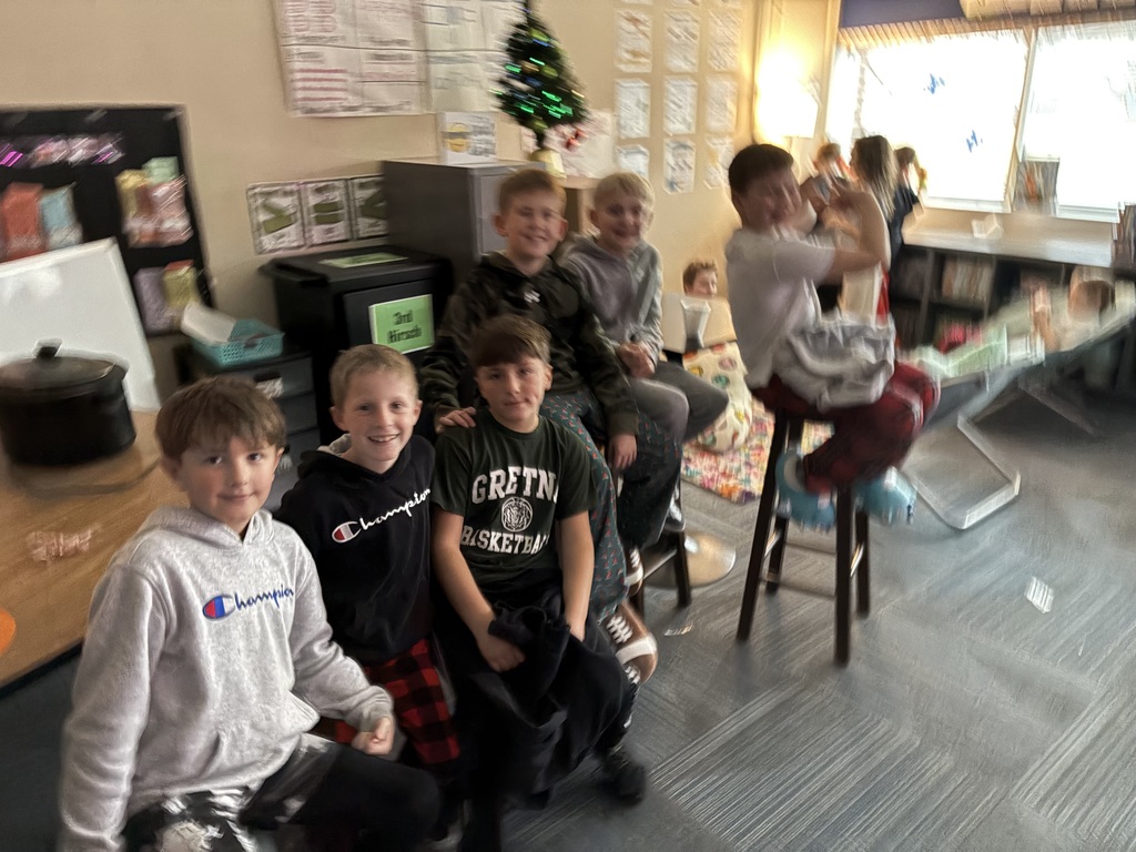 Group of boys sitting in a classroom around a table.