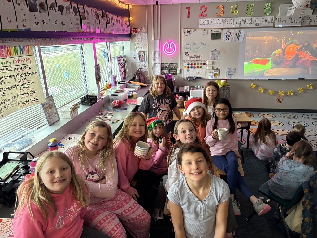 Group of girls sitting on chairs holding coffee cups up.