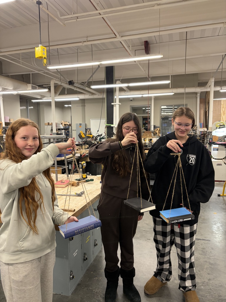 Photo of three female students holding their bookshelves made from recycled books.