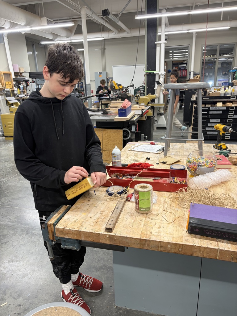 Photo of a male student stringing twine through a book to make his bookshelf.