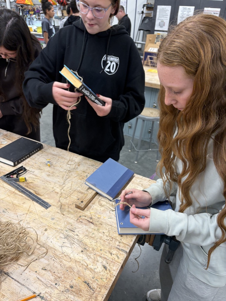 Photo of a female student stringing twine through a book to make her bookshelf.