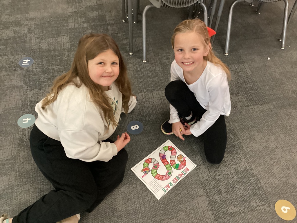 two students playing a game on the floor of a classroom