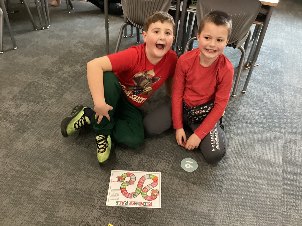 students smiling for a phoot while playing a game on the floor of a classroom
