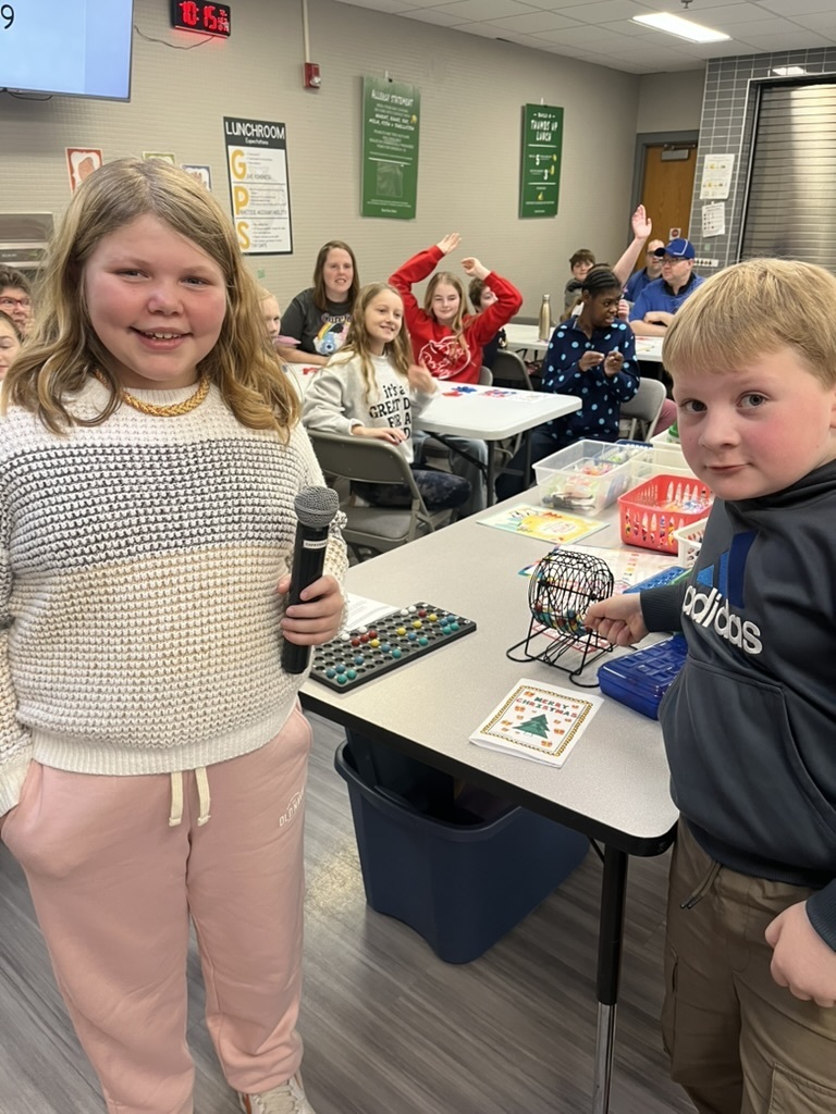 Group of students in a cafeteria sitting at tables playing bingo.