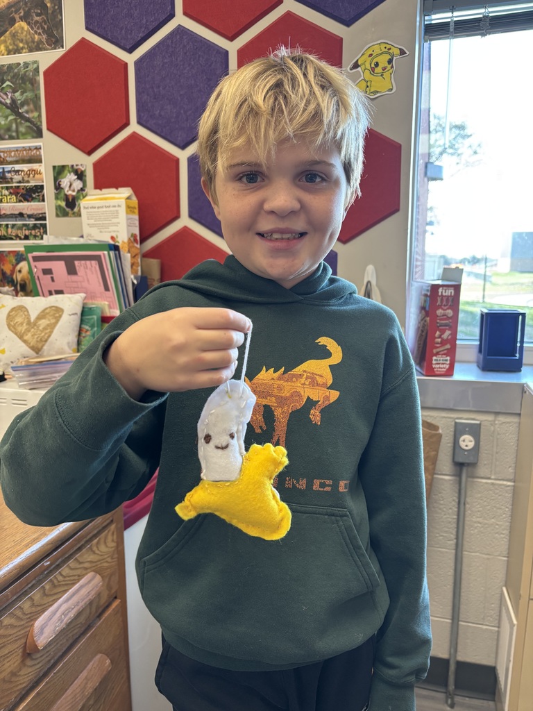 Student holding a white and yellow knitted yarn decoration.