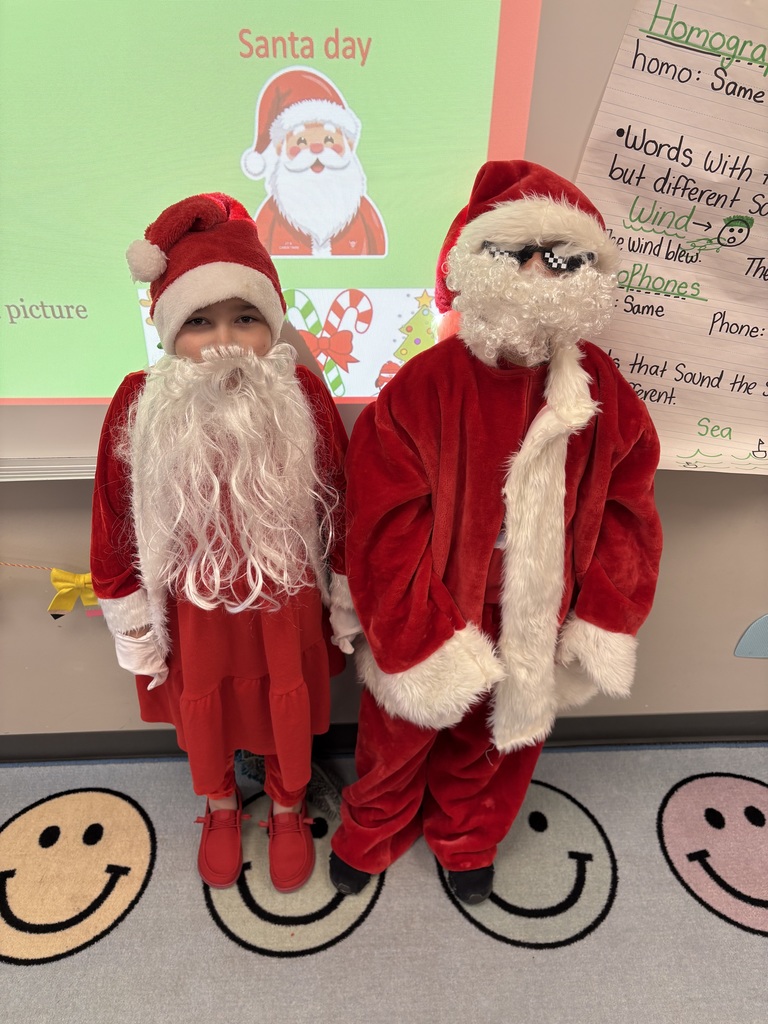 Two students dressed in red Santa coats and hats.
