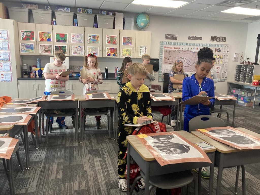 Fourth Graders are standing behind desks looking at their silhouettes, writing notes.