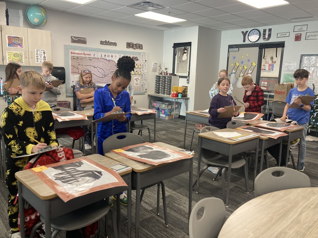 Fourth Graders are standing behind desks looking at their silhouettes, writing notes.