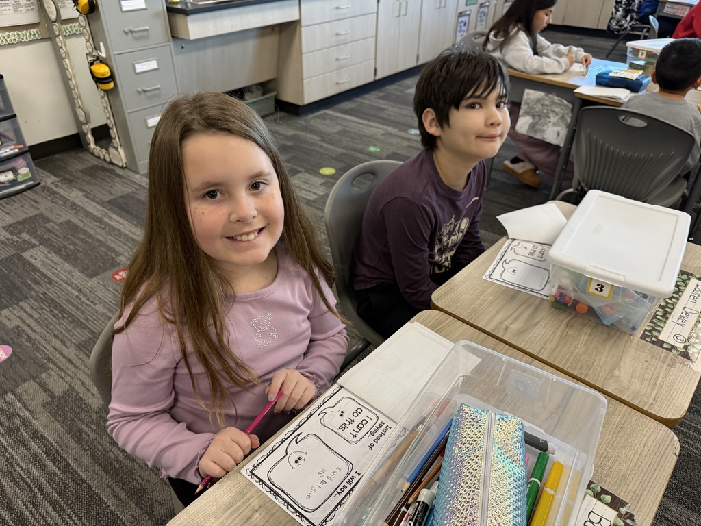 A fifth grade girl and boy are working at a desk on a booklet about Growth Mindset.