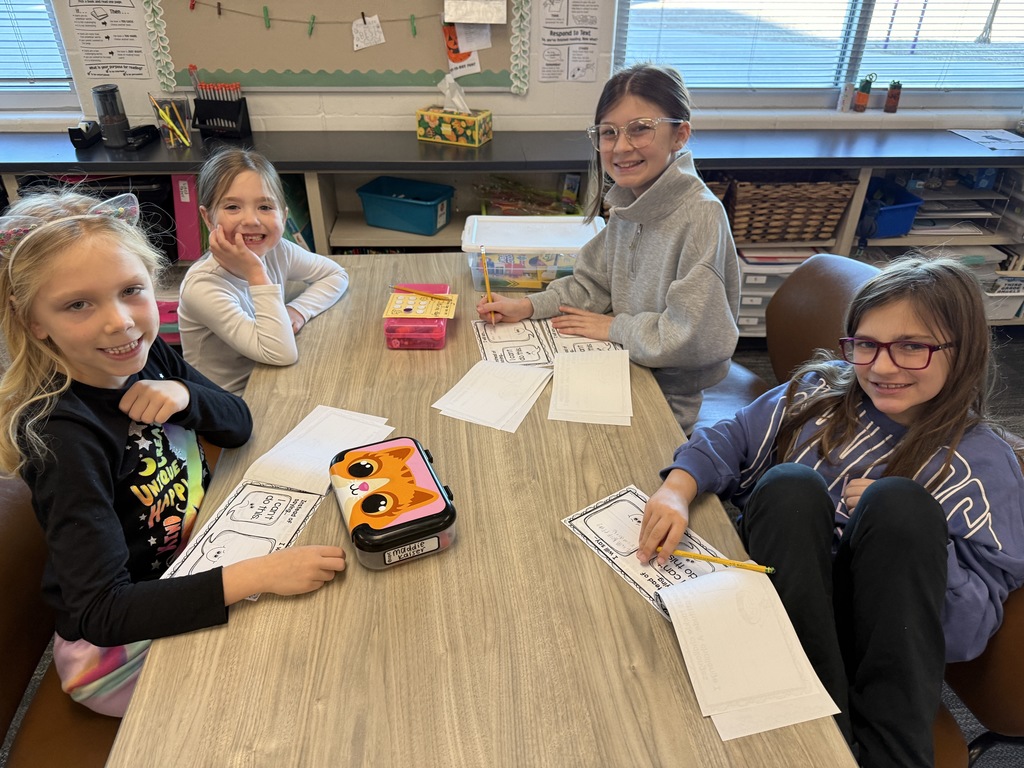 A table of two third grade girls and two kindergarten girls work on packets about growth mindset