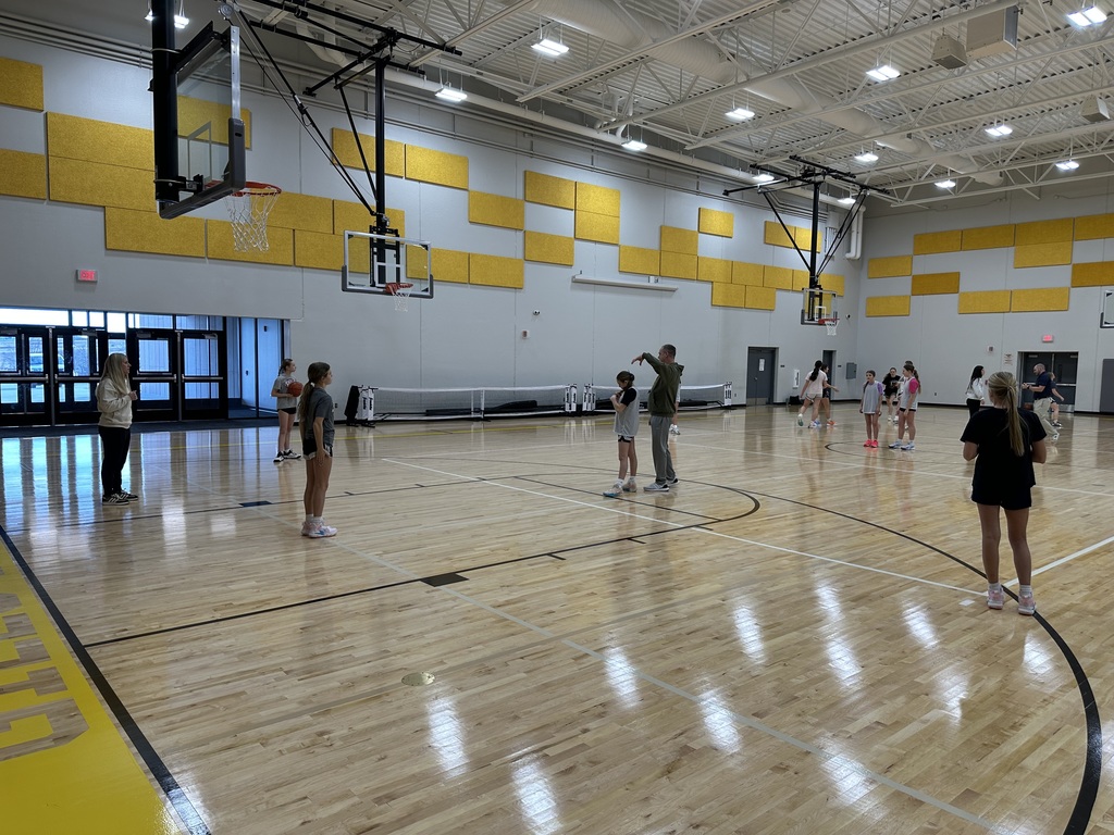 Girls are practicing basketball in a gym. 
