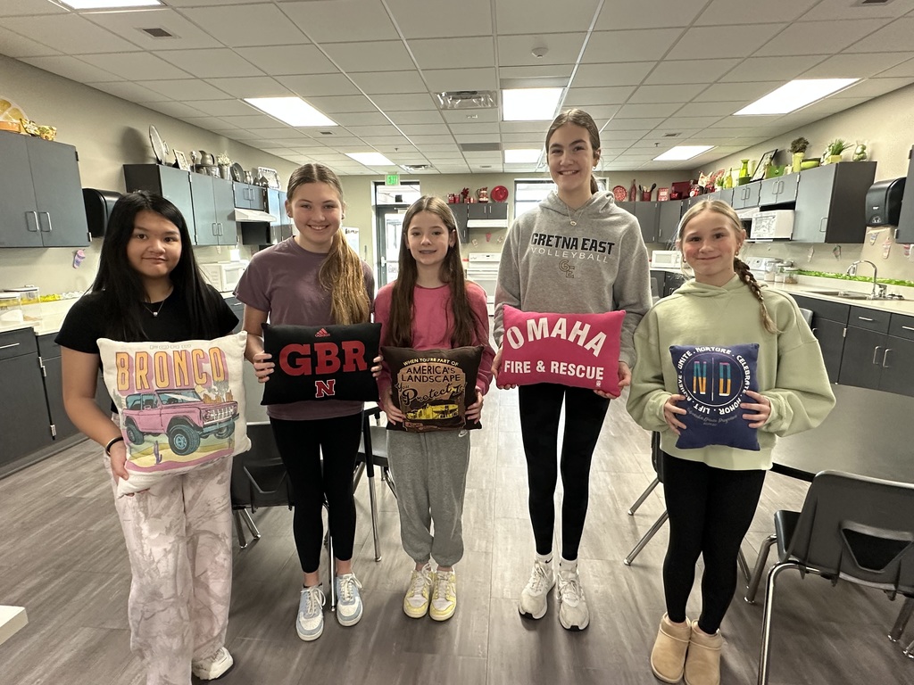 Photo of five female students holding the pillows they sewed for class.