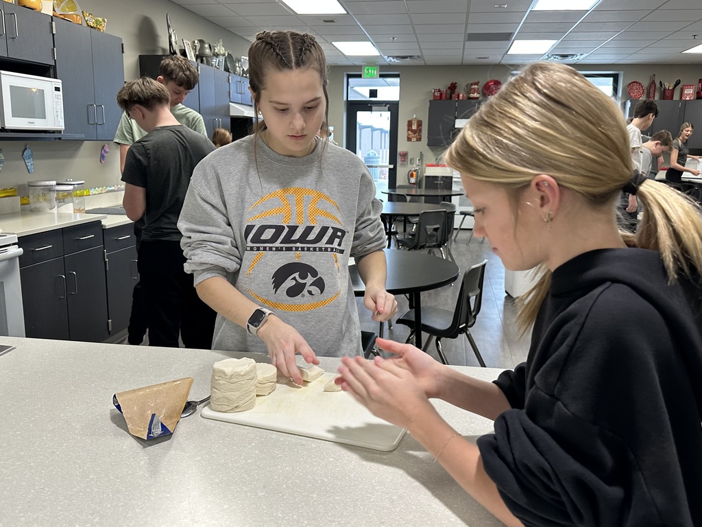 Photo of two female students rolling chunks of biscuit dough into balls.