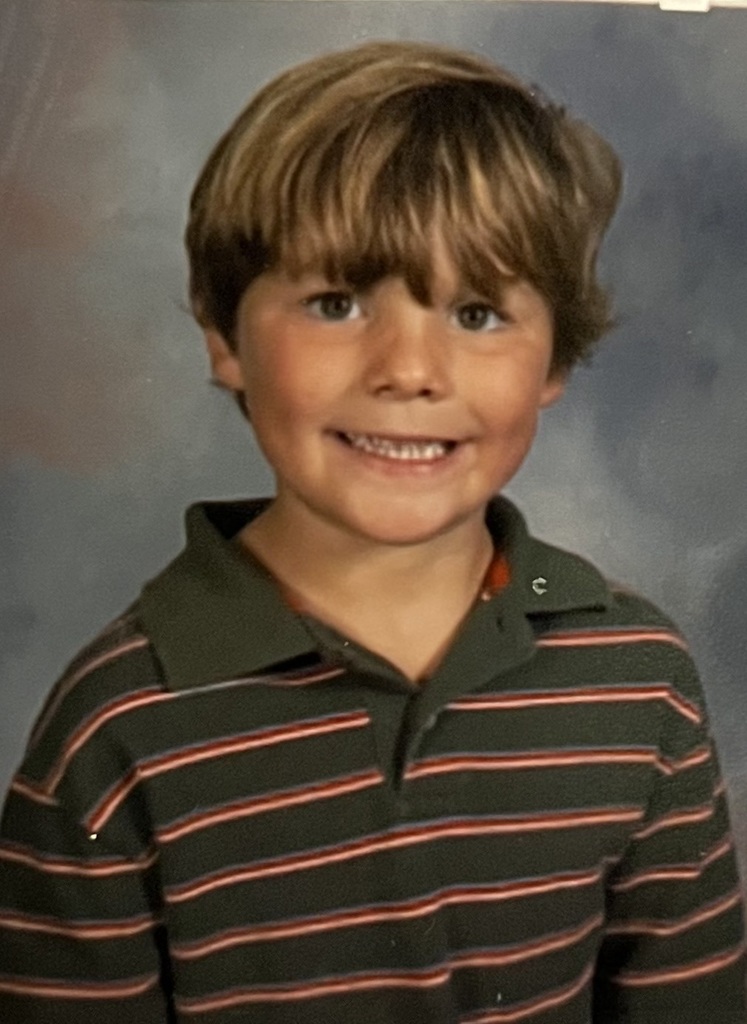 A boy wearing a green and red striped shirt.