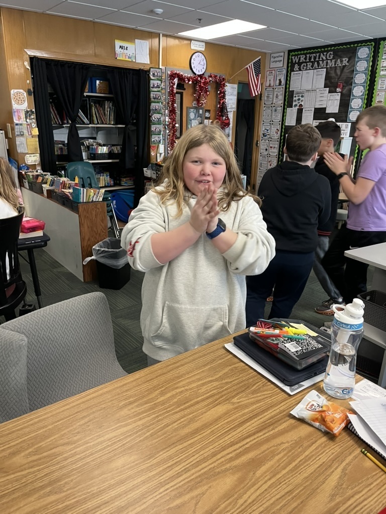 Girl standing and clapping with a group of boys standing in the background