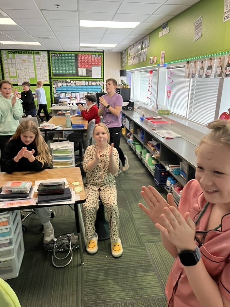 Students clapping while standing and sitting in a classroom