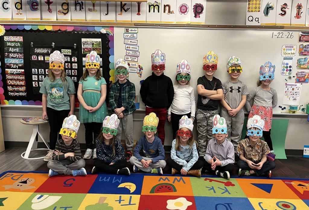 Group of students, some standing and some sitting with 100 glasses on and 100th day of school hats