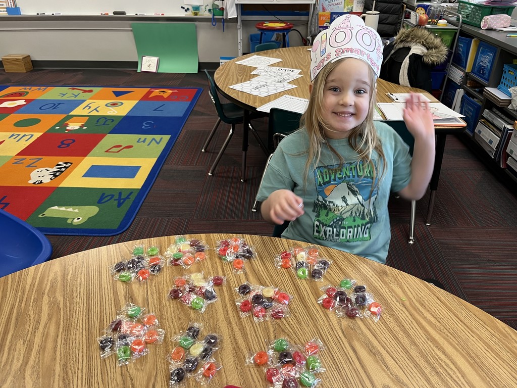 Girl sitting at a table with a 100 day scoop and sort on table