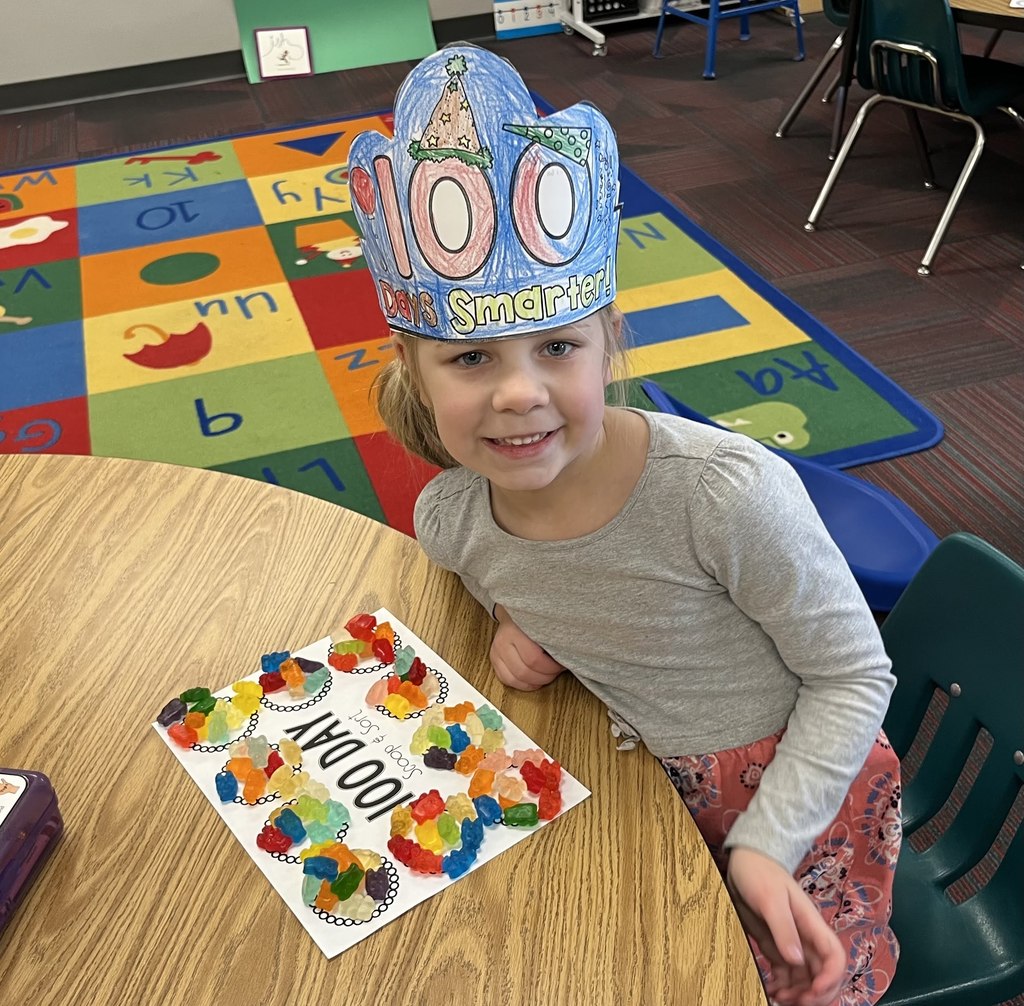 Girl sitting at a table with a 100 day scoop and sort on table