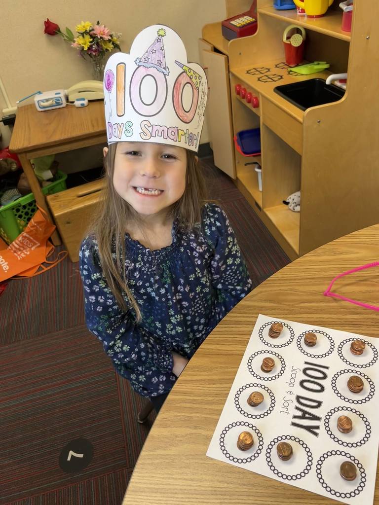 Girl sitting at a table with a 100 day scoop and sort on table