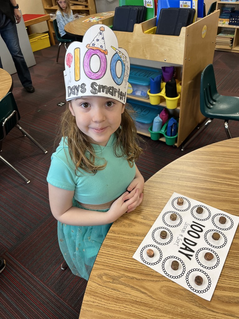 Girl sitting at a table with a 100 day scoop and sort on table