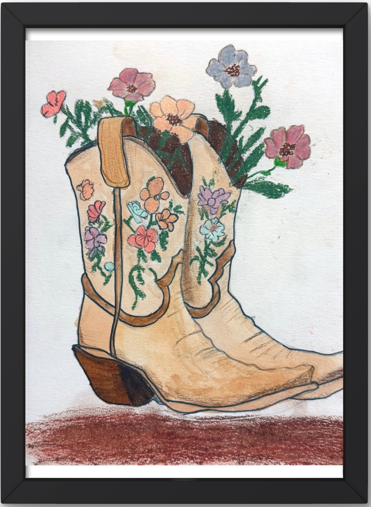 a framed chalk artwork of cowgirl brown boots with flowers design and fresh flowers in the boots standing upright on a dirt ground