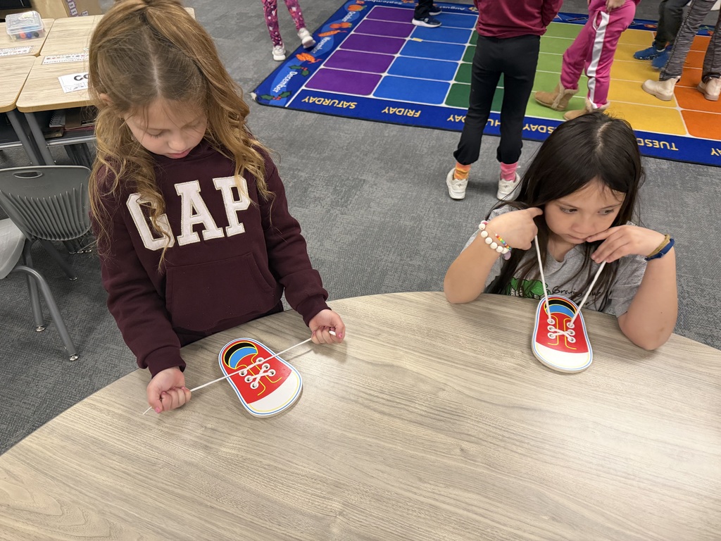 students practicing how to tie shoes in a classroom