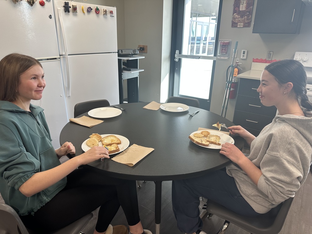 Photo of two students sitting at a table eating.