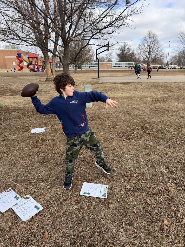 Boy wearing a blue sweatshirt throwing a football outside